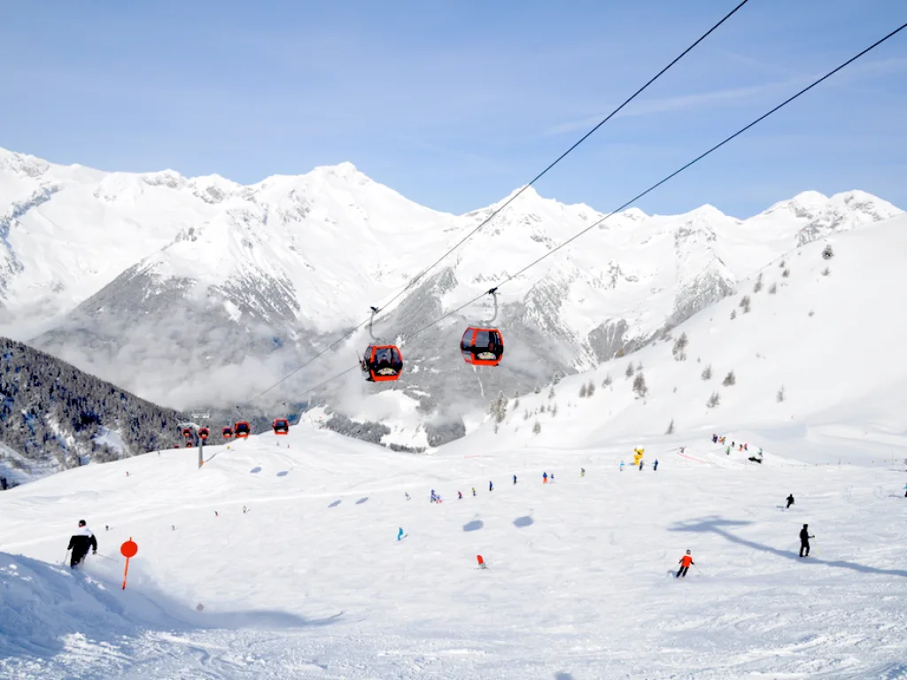 Weites Bergpanorama mit Piste und Gondelbahn.